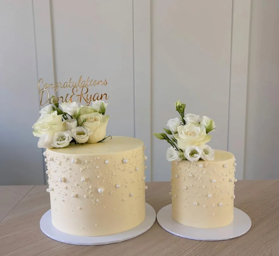 Two ivory wedding cakes with white roses and delicate pearl decorations