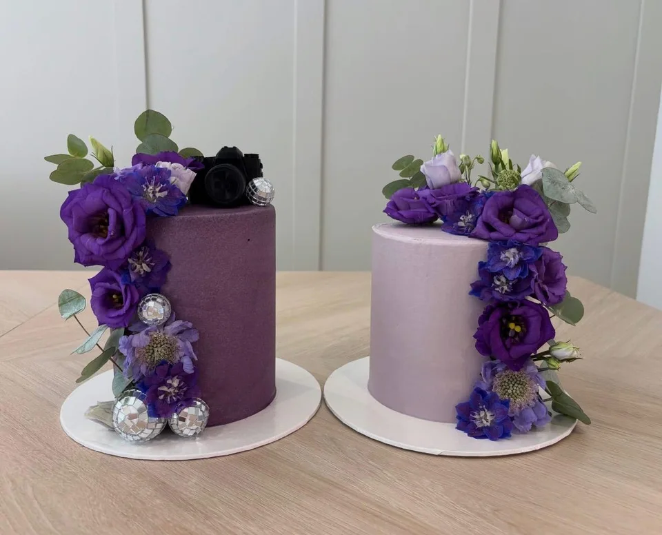 A pair of lilac cakes with purple flowers, eucalyptus and silver decorations