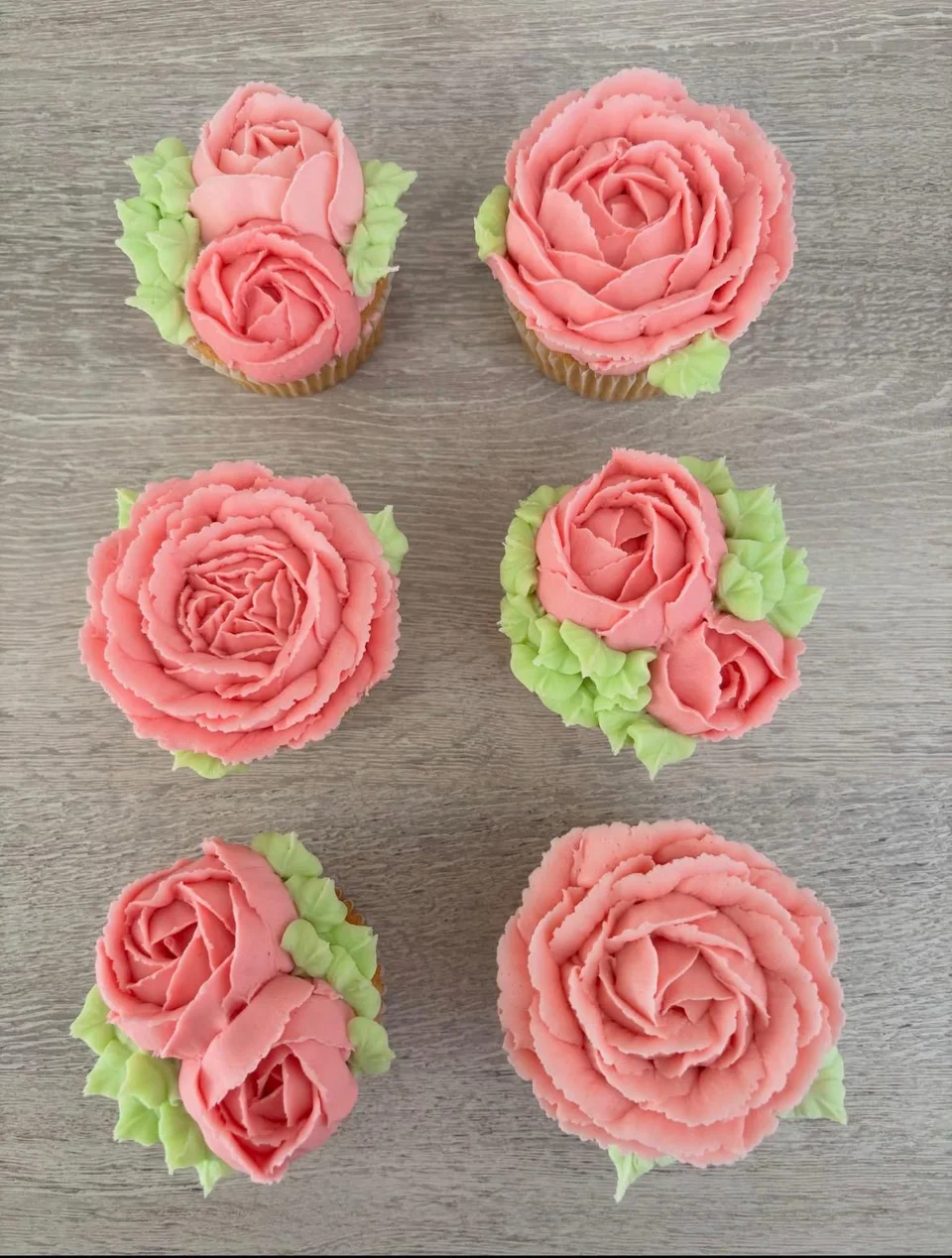 Le Mon’s coral-pink buttercream rose cupcakes with hand-piped petals and green leaves